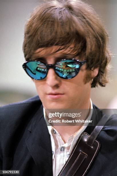 Beatles singer and songwriter John Lennon wearing mirrored sunglasses, in which his organ keyboard and Rickenbacker guitar are reflected, August 1965.