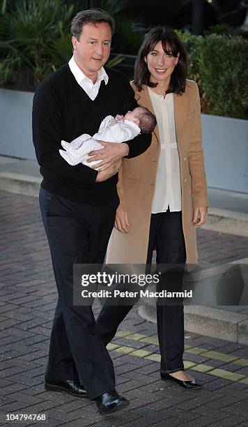 Prime Minister David Cameron holds his baby daughter Florence as he arrives at the Conservative Party Conference with his wife Samantha on October 5,...