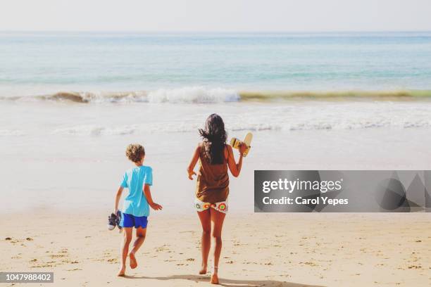 two kids walking down to beach.rear view - portugal beach stock pictures, royalty-free photos & images