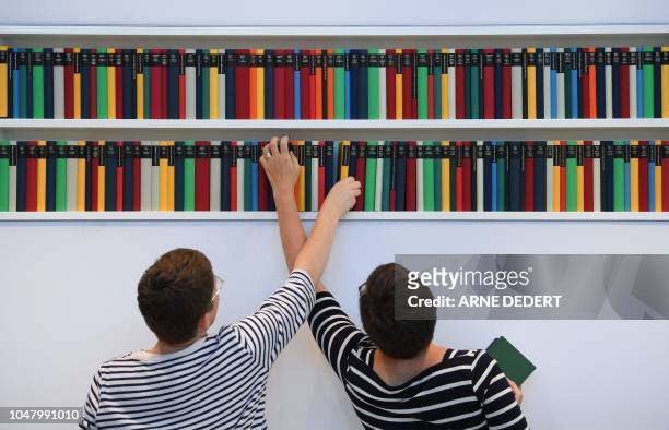Two women arrange books in a shelf at the booth of the Diogenes publishing house as preparaatins are under way for the Frankfurt Book Fair on October...