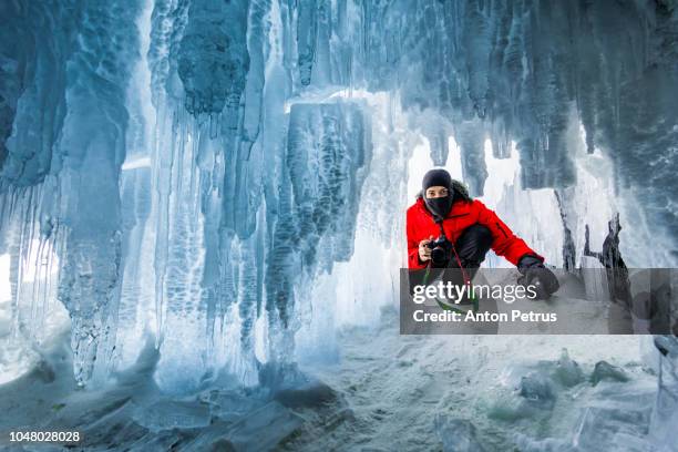 photographer in the ice cave at sunset. baikal, russia - estalactite imagens e fotografias de stock