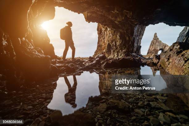 explorer in a cave at sunset in campiecho beach in asturias, spain - photographer seascape stock pictures, royalty-free photos & images