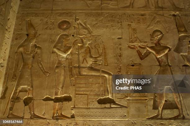 Egypt. Abydos. Temple of Seti I. New Kingdom. 19th Dynasty. The Pharaoh Seti I offering a staue of Maat to gods Osiris, Isis and Horus. Relief....