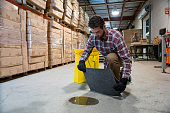 A man in a warehouse putting an absorbent mat on a puddle of oil