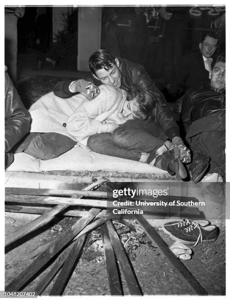 Sidelights of Rose Parade Spectators line sidewalks...Ambulance...Casualty being carried on stretcher...Group keeps warm at small street...