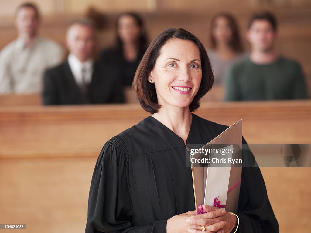 Smiling judge holding file in courtroom