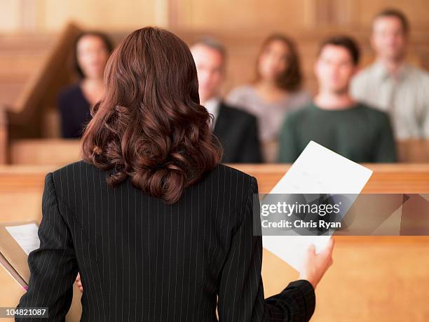 lawyer holding document and speaking to jury in courtroom - court room stock pictures, royalty-free photos & images