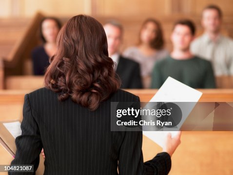 Lawyer holding document and speaking to jury in courtroom Lawyer holding document and speaking to jury in courtroom