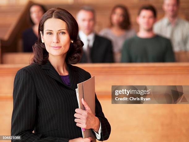 smiling lawyer holding file in courtroom - uk courtroom stock pictures, royalty-free photos & images