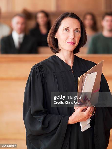 confident judge holding file in courtroom - judge stockfoto's en -beelden