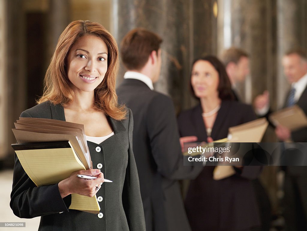 Smiling lawyer holding files in corridor