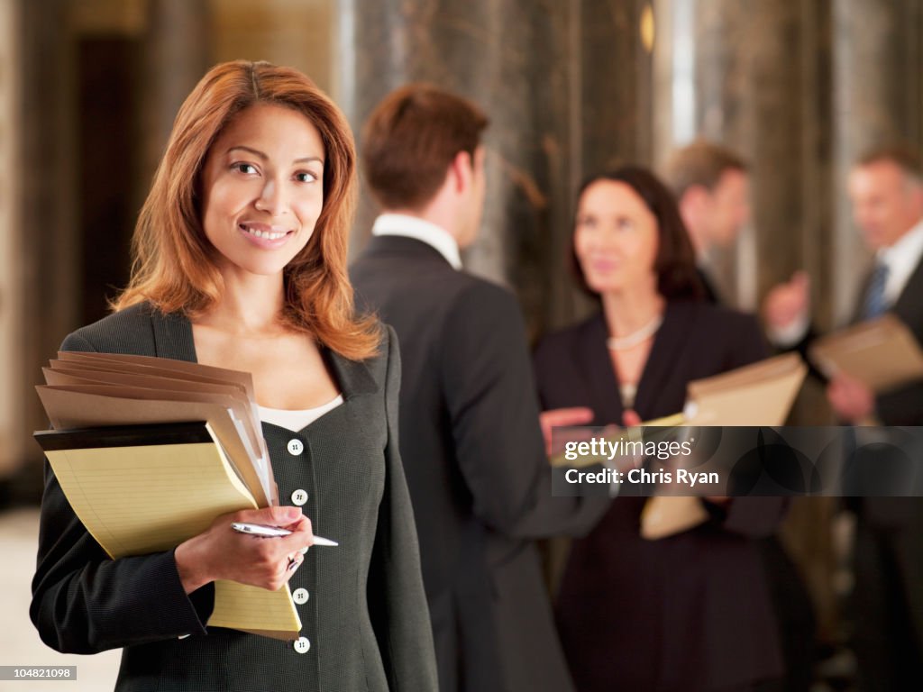 Smiling lawyer holding files in corridor