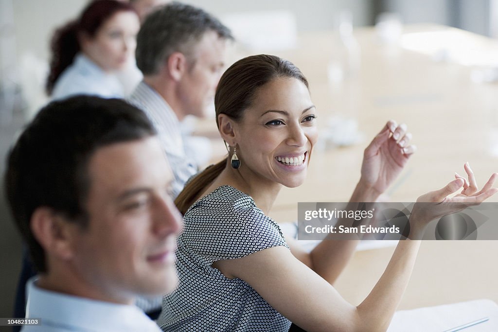 Empresária sorridente balançando um bastão em reunião na sala de conferências
