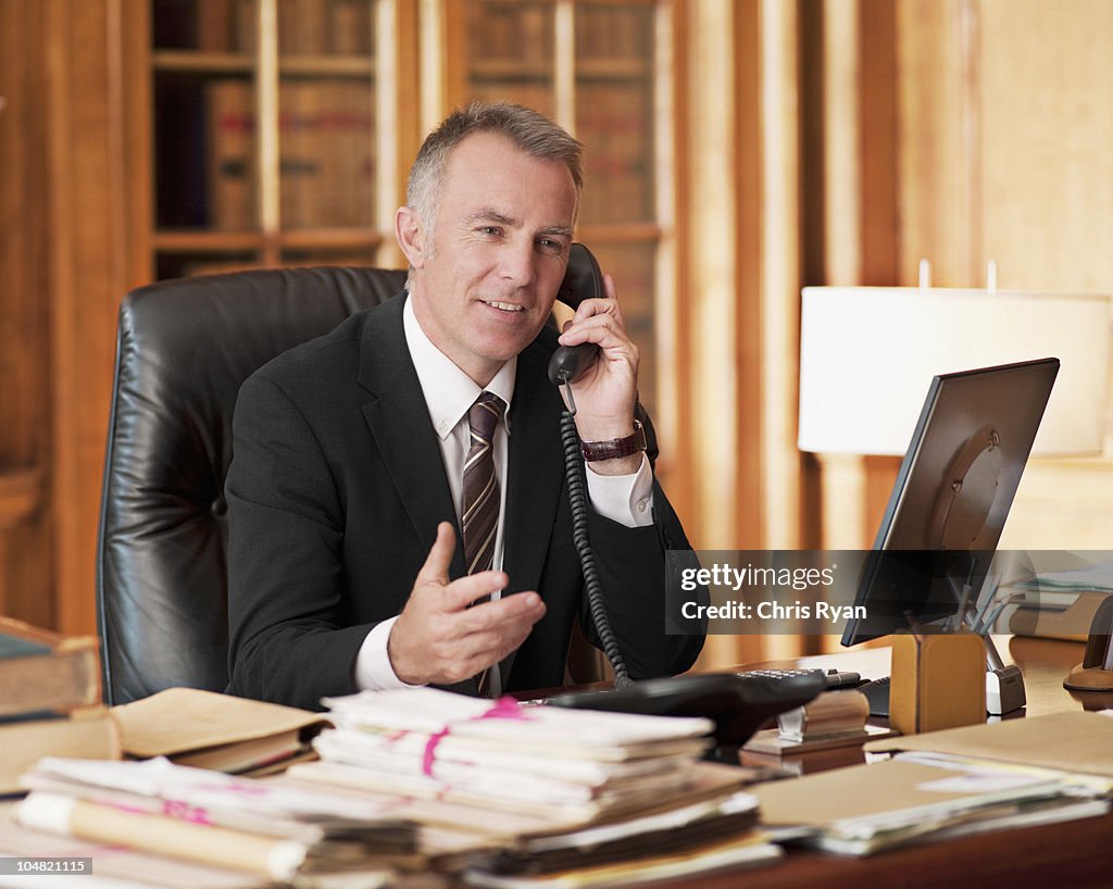 Advogado falando no telefone e balançando um bastão em Escritório