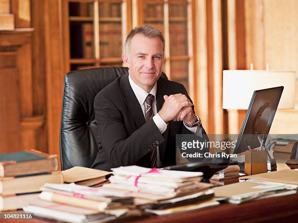 lächeln anwalt sitzen am schreibtisch in büro - lawyer stock-fotos und bilder