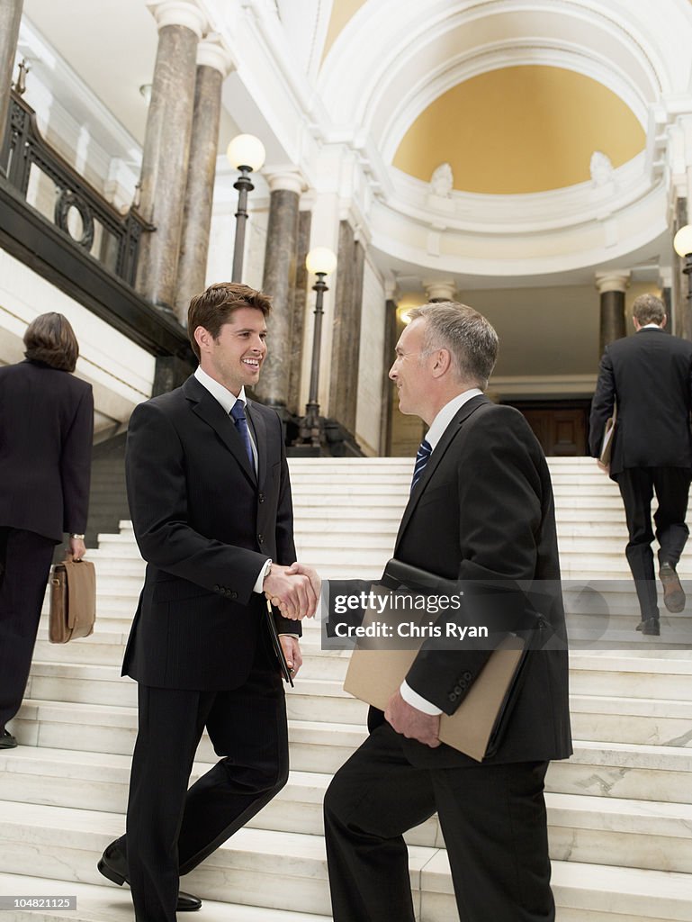 Smiling lawyers shaking hands on stairs
