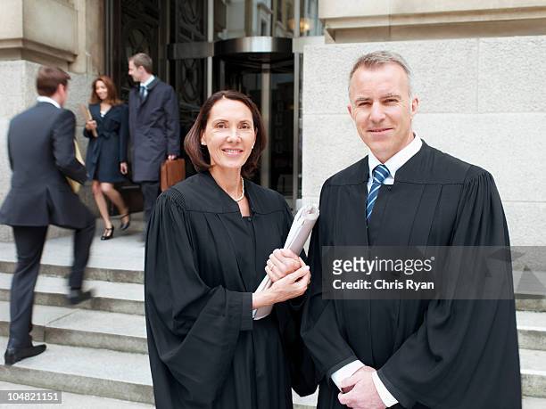smiling judges in robes standing outside courthouse - advocaat juridisch beroep stockfoto's en -beelden