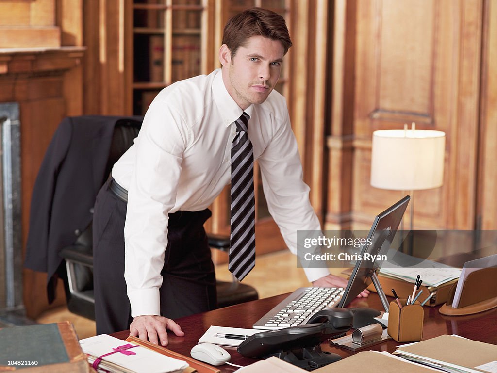 Serious lawyer working at laptop in office