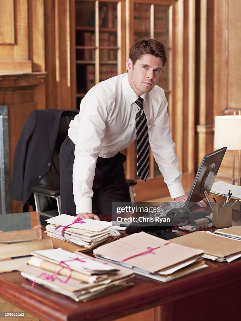 Serious lawyer working at laptop in office
