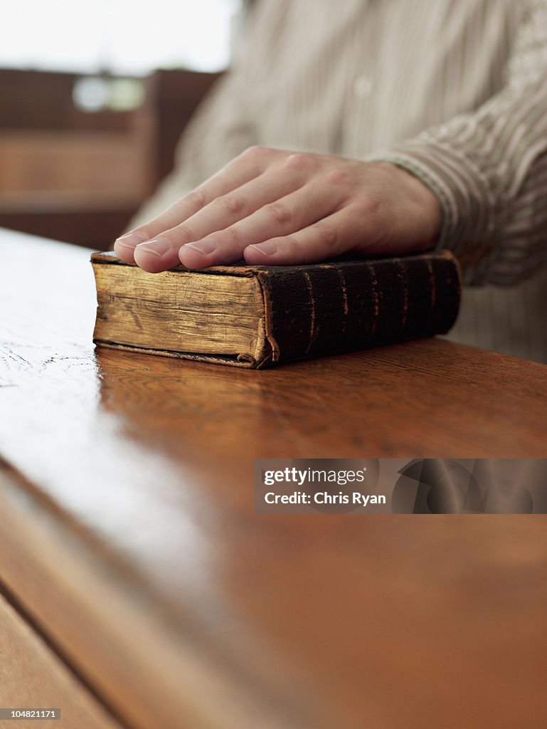 Hand of witness on Bible in courtroom