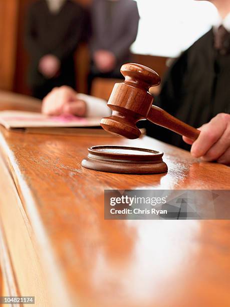 close up of judge raising gavel in courtroom - court judge stock pictures, royalty-free photos & images