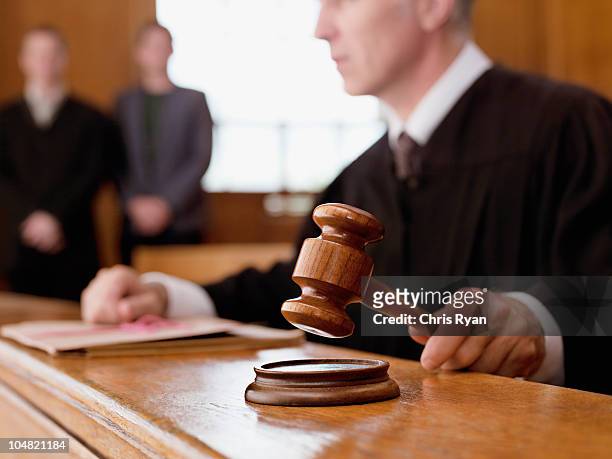 judge holding gavel in courtroom - gerechtigheid stockfoto's en -beelden