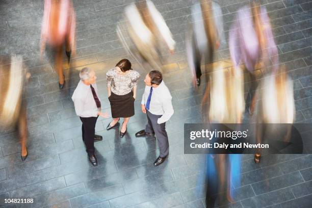 people rushing past business people talking - ignorance foto e immagini stock