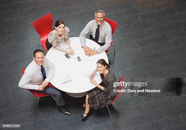 smiling business people sitting at round table and having a meeting - round four bildbanksfoton och bilder