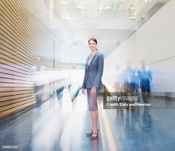 business people rushing past smiling businesswoman in lobby - female streaking stockfoto's en -beelden