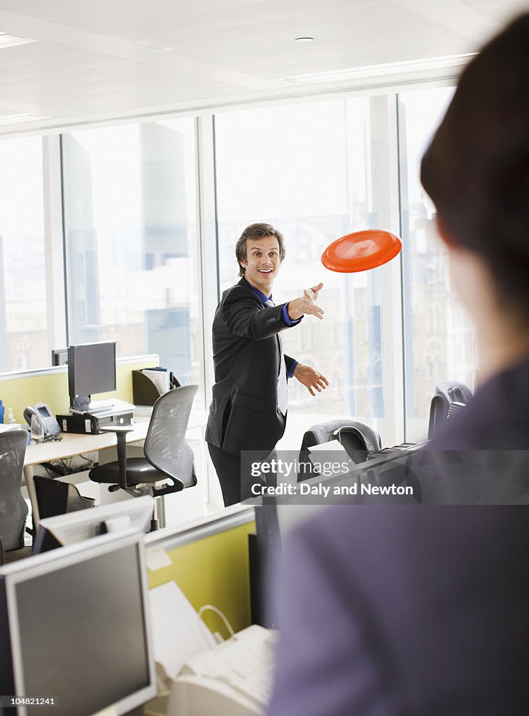 Businessman throwing plastic disc in office