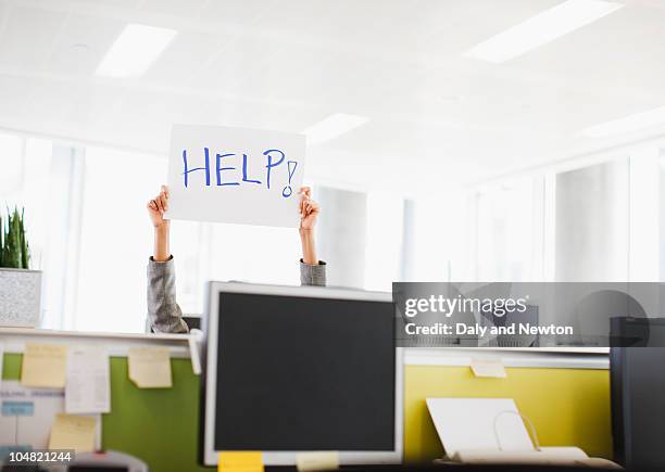 businesswoman holding help sign overhead in office - help single word fotografías e imágenes de stock