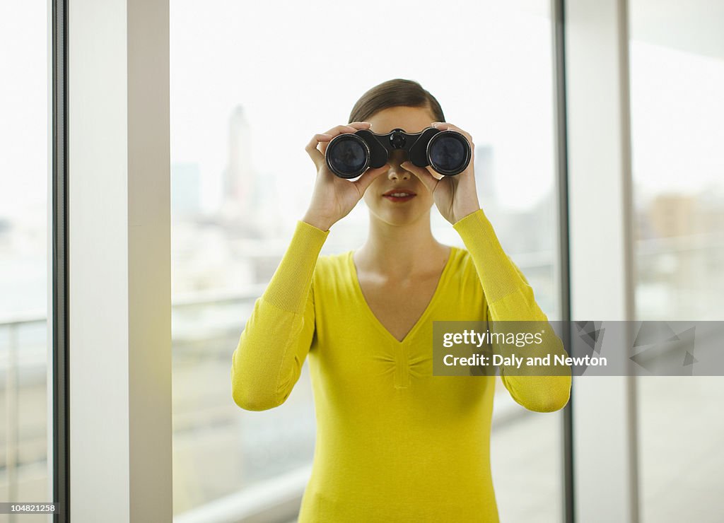 Businesswoman looking through binoculars