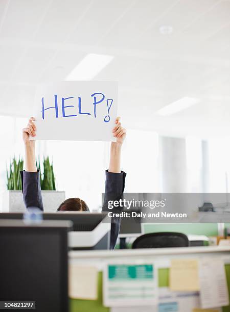 businesswoman holding help sign overhead in office - help engels woord stockfoto's en -beelden