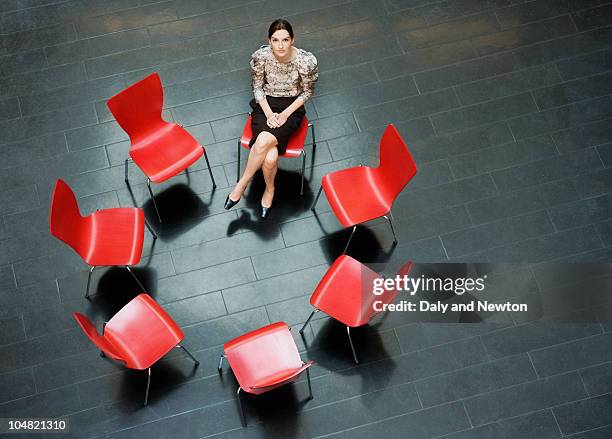 businesswoman sitting alone in circle of chairs - middelgrote groep dingen stockfoto's en -beelden