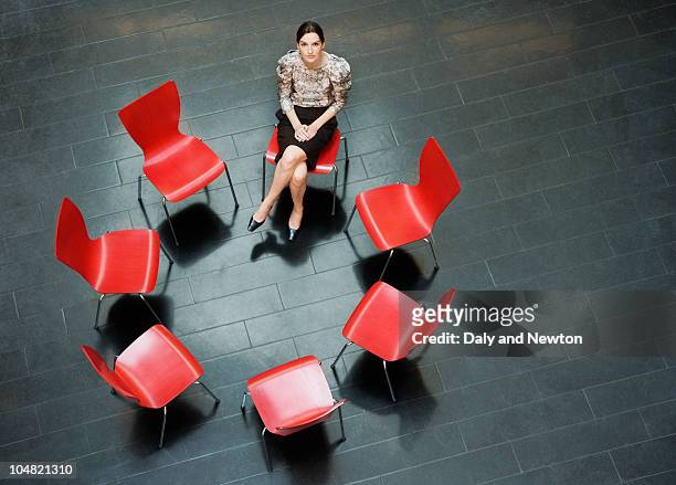 businesswoman sitting alone in circle of chairs - red office chair stock pictures, royalty-free photos & images
