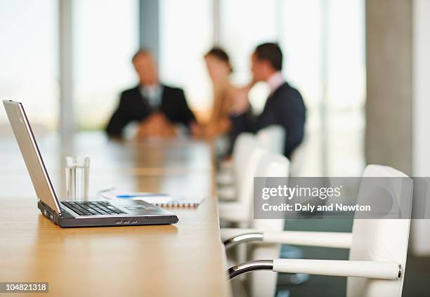laptop on conference room table with business people in background - absence photos et images de collection