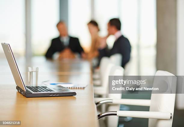 laptop on conference room table with business people in background - erase photos et images de collection