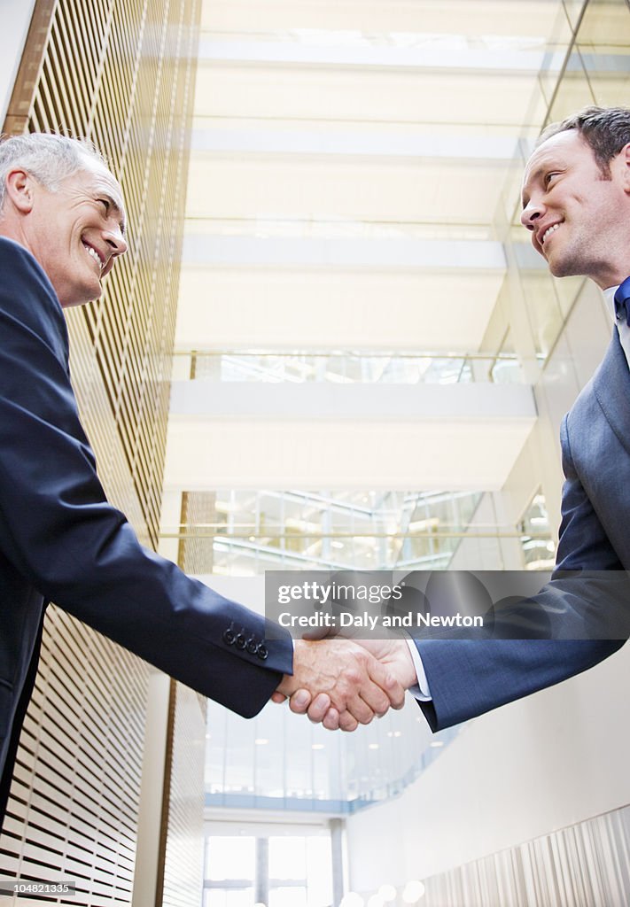 Smiling businessmen shaking hands in lobby