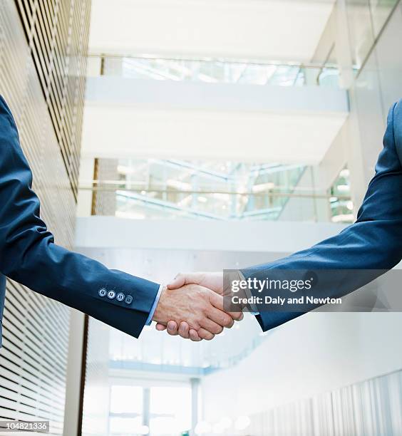 businessmen shaking hands in lobby - mid adult men fotografías e imágenes de stock