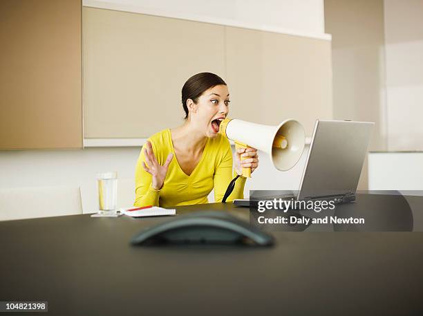 businesswoman yelling at laptop with bullhorn in conference room - office anger stock pictures, royalty-free photos & images