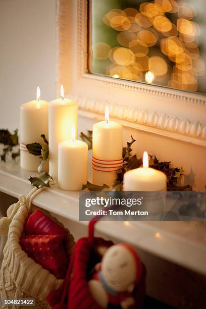 candles lit on mantelpiece with christmas stockings - christmas candles stockfoto's en -beelden