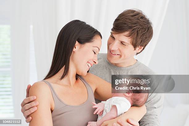 smiling parents holding baby - newborn baby and parents stock pictures, royalty-free photos & images