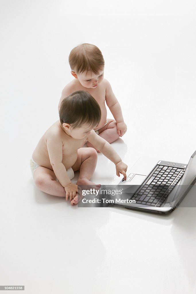 Babies on floor using laptop