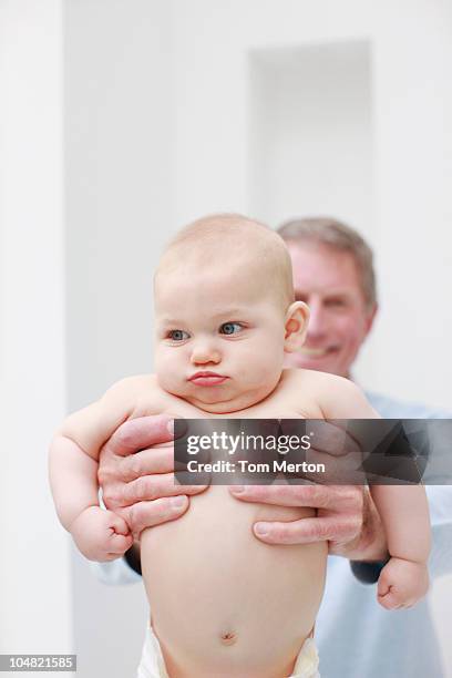 smiling grandfather holding baby - active baby boomer stock pictures, royalty-free photos & images