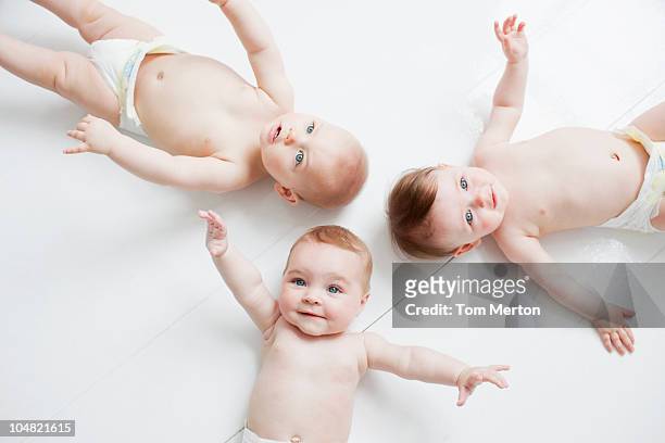 sonriente bebé que descansan en el suelo - three people fotografías e imágenes de stock