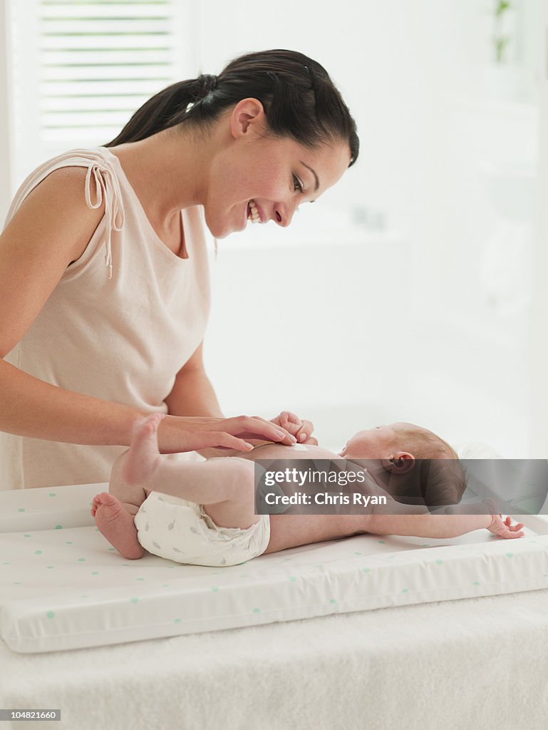 Mother changing babys diaper on changing table