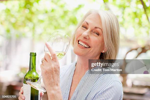 smiling woman drinking white wine - senior women wine stock pictures, royalty-free photos & images