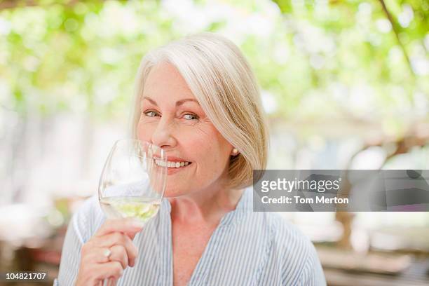 smiling woman drinking white wine - senior women wine stock pictures, royalty-free photos & images