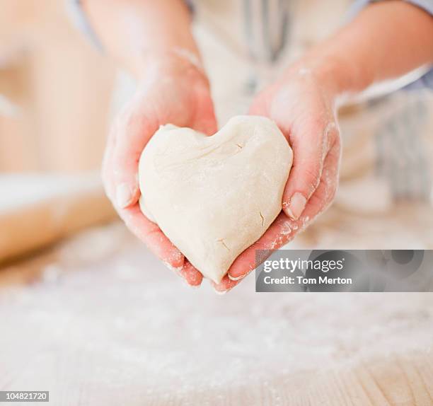 close up of woman holding heart-shape dough - bread love stockfoto's en -beelden