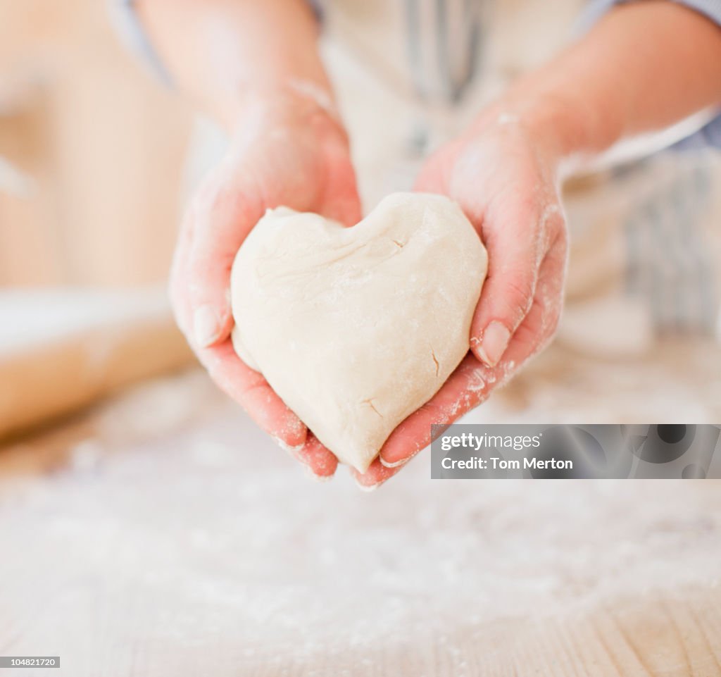 Close up of woman holding heart-shape dough